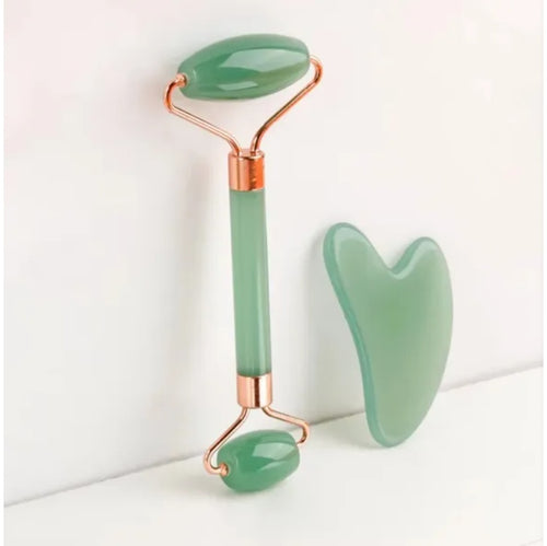 Green resin face roller and gua sha board on a white background
