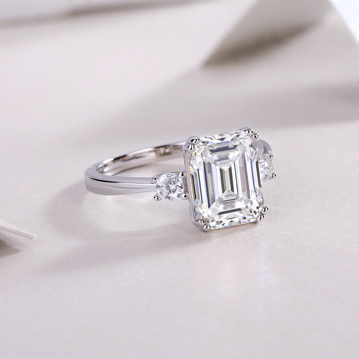 Emerald-cut moissanite three-stone ring, angled view