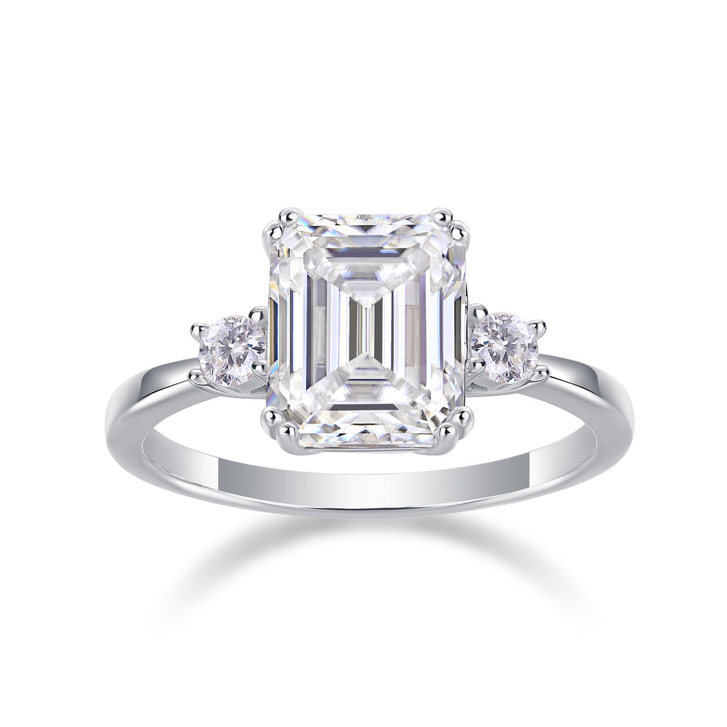 Emerald-cut moissanite three-stone ring on a white background